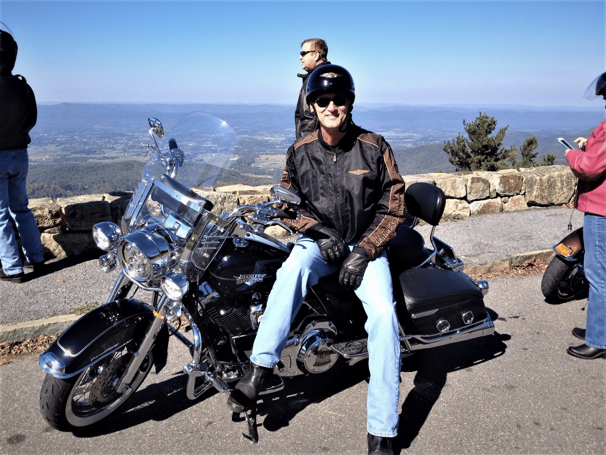 Man wearing motorcycle helmet sitting on a Harley-Davidson with a scenic view behind